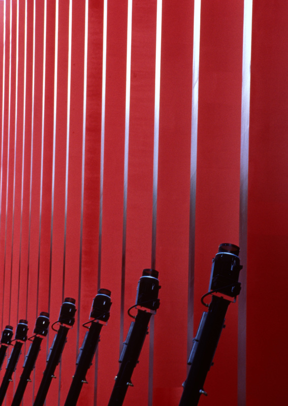 Red wall with vertical steel strips and tilted floodlights - CityLink, Melbourne, 1999